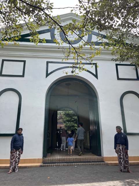 Two male abdi dalem standing by an entrance at a royal palace in Yogyakarta